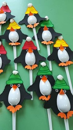 there are many penguin cupcake toppers on the stick with hats and capes