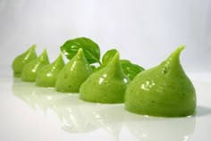 four green pears lined up on a white surface