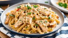 a white plate topped with pasta covered in sauce and garnished with parsley