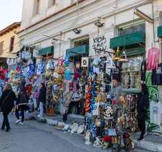 people are walking around in front of a store with lots of items on the outside