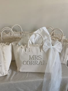 four white purses sitting on top of a table covered in ruffled fabric and bows