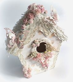 a white birdhouse with pink flowers on it's roof and a butterfly in the window