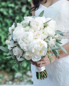 a bride holding a bouquet of white flowers