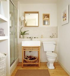 a white toilet sitting next to a sink in a bathroom under a mirror above a wooden shelf