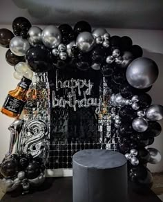 a black and silver birthday party with balloons, decorations and liquor bottles on the table