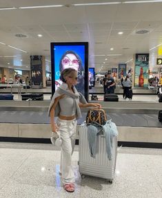 a woman standing in an airport with her luggage