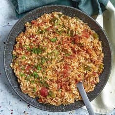 a plate full of rice and vegetables with a spoon in it on a blue table cloth