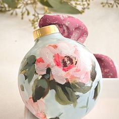 two vases with flowers painted on them sitting next to some pink and green leaves