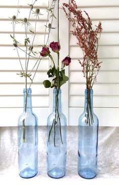 three blue glass bottles with flowers in them