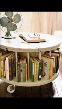 a round table with books on it in front of a fan