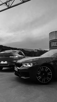 two cars are parked next to each other in a parking lot near a water tower