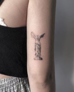 a woman's arm with a statue tattoo on the left side of her body