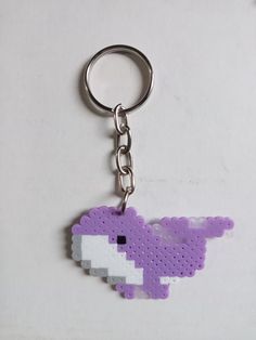 a purple pixel keychain is shown on a white surface and has an image of a bird in the shape of a pixel