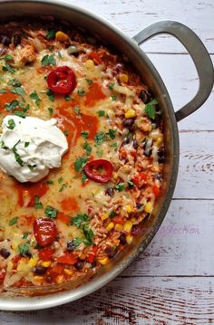 a large pot filled with food on top of a white wooden table next to a spoon