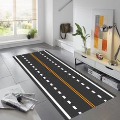 a black and white rug with yellow lines on the floor in front of a window