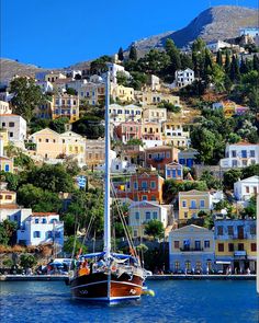 a boat floating on top of a body of water next to a hillside covered in houses