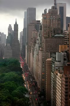 the city is full of tall buildings and green trees on both sides of the street