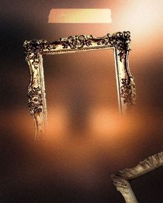 an ornate gold framed mirror hanging on the wall next to a white chair and lamp