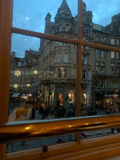 a window with people walking in the street outside at night, as seen from inside