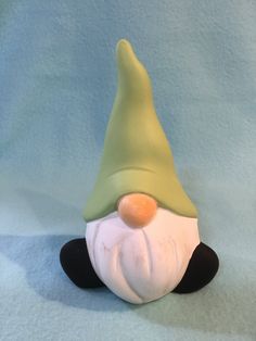 a small green and white gnome figurine on a blue background