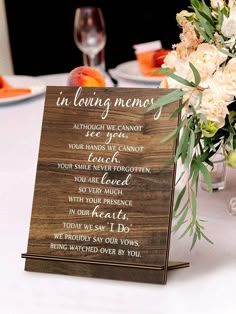 a wooden sign sitting on top of a table next to a vase filled with flowers