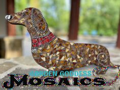 a mosaic dachshund is sitting on top of a stone slab with the words garden goddess mosaics below it