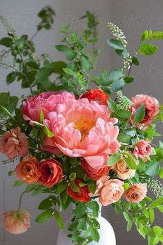 a white vase filled with lots of pink and orange flowers