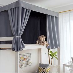 a loft bed with curtains and a teddy bear on top