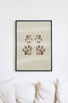 a dog paw print hanging on the wall above a bed with white pillows and throw pillows