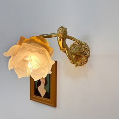 a lamp that is on the wall next to a framed photo with a woman's face