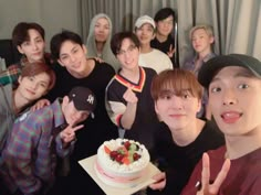 a group of young people posing for a photo with a cake on the table in front of them