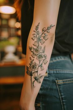 a woman's arm with flowers on it and leaves in the middle of her arm