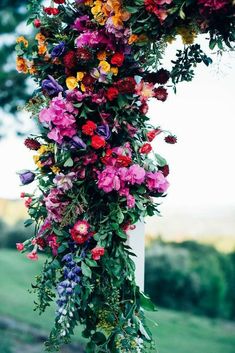 a bunch of flowers that are hanging from a pole in front of some grass and trees