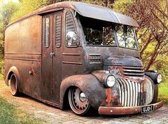 an old truck is parked on the side of the road in front of some trees