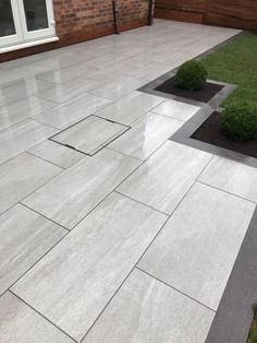 an outdoor patio with grey tiles and grass