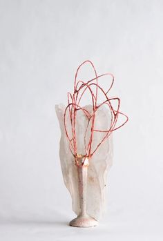 a white vase with red branches in it