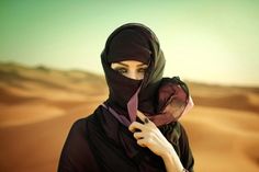 a woman wearing a black hijab in the desert