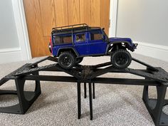 a blue toy truck is on top of a metal structure in front of a door