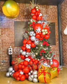 a christmas tree decorated with red, silver and gold ornaments in front of a brick wall