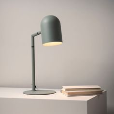 a desk lamp sitting on top of a table next to a stack of books and a book