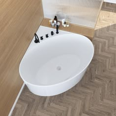 a white bath tub sitting on top of a wooden floor next to a sink and faucet