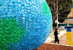 a woman walking past a large blue and green ball with bubbles on it's side