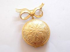 This vintage 70's Avon Perfume gold tone brooch, signed Avon products New York. It opens with a secure hinged clasp on the locket area to reveal solid perfume. This area has a diameter of 1.25 inches/3.2cm. The whole brooch fastens with a secure roll lock safety clasp & has a length of 9.6 inches/25.3cm and a width of 1.41 inches/3.6cm. A beautiful locket to wear, and it has a lovely perfume to rub, along you neck or wrist. Locket will be wrapped & place in a gift box. *SHIPPING* US ORDERS-ship through the USPS First Class, shipping takes 2-5  business days with delivery confirmation.  INTERNATIONAL ORDERS are shipped through the USPS International First Class, shipping time is 2-4 weeks depending on location. If you have any questions please send me a convo, I will reply as soon as possib Vintage Medallion Brooch For Wedding, Vintage Medallion Brooches For Wedding, Formal Gold Locket Brooches, Gold Locket Brooch For Collectors, Vintage Gold-tone Brooches For Formal Occasions, Vintage Medallion Brooches For Formal Occasion, Gold Brooches With Vintage Charm For Gift, Gold Brooches With Vintage Charm As Gift, Gold Medallion Brooch For Formal Occasions