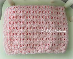 a pink crocheted blanket sitting on top of a white chair