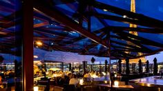 people are sitting at tables in an outdoor restaurant with the eiffel tower in the background