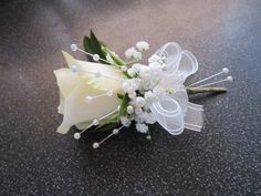 a white rose and baby's breath boutonniere on a black table