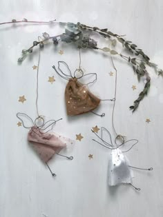 three ornaments are hanging on the wall with stars and plants around them, one is shaped like a bell