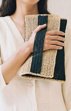 a woman holding a crocheted purse in her hands