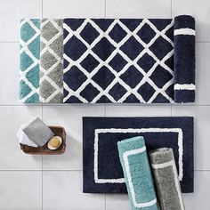 bathroom rugs in various colors and patterns on the floor next to towels, soap dispenser and toothbrush