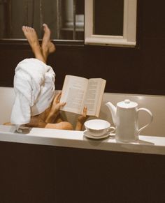 a person laying in a bathtub reading a book